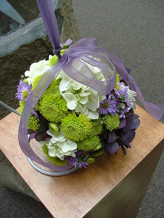 Свадебный букет круглой формы, который крепится на запястье с помощью ленты: https://en.wikipedia.org/wiki/Flower_bouquet#/media/File:Wedding_pomander_with_mum,_hydrangea_and_aster.jpg